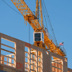 Yellow crane with wood framing of an under construction building in the foreground